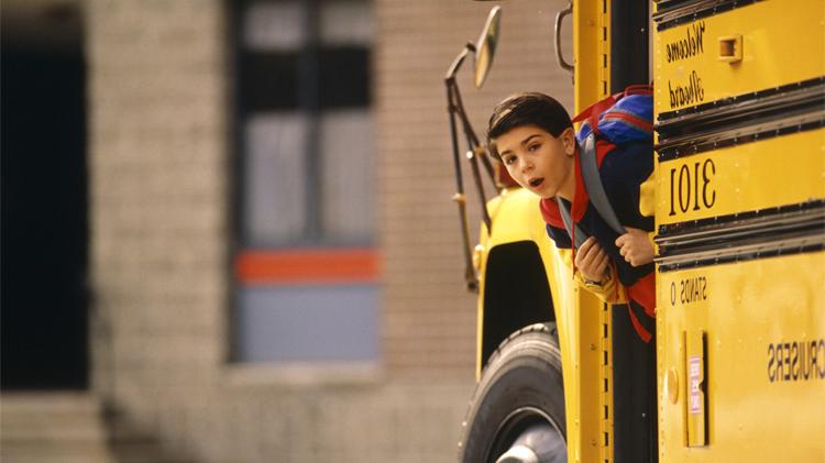 Boy using school bus safety by checking his surroundings before he exits the school bus.